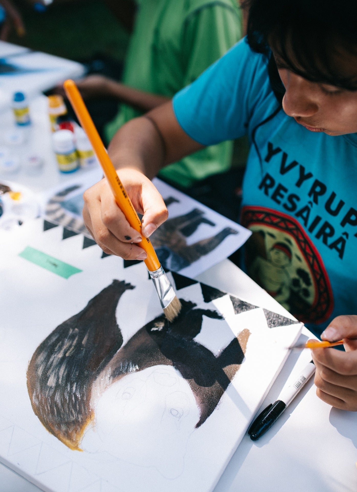 Mãos pintando uma onça em tela